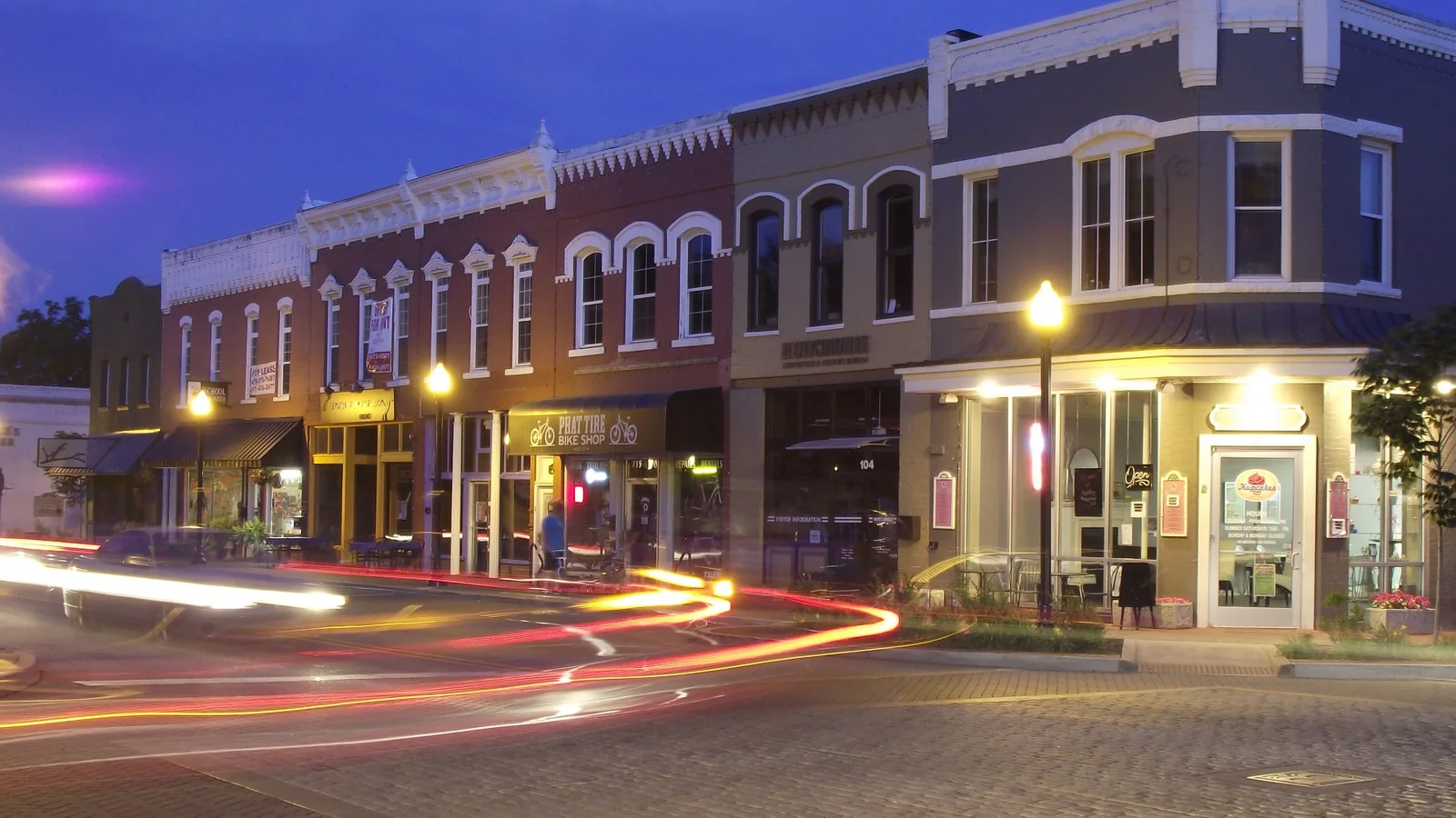 Central Avenue storefronts glowing at night in Bentonville