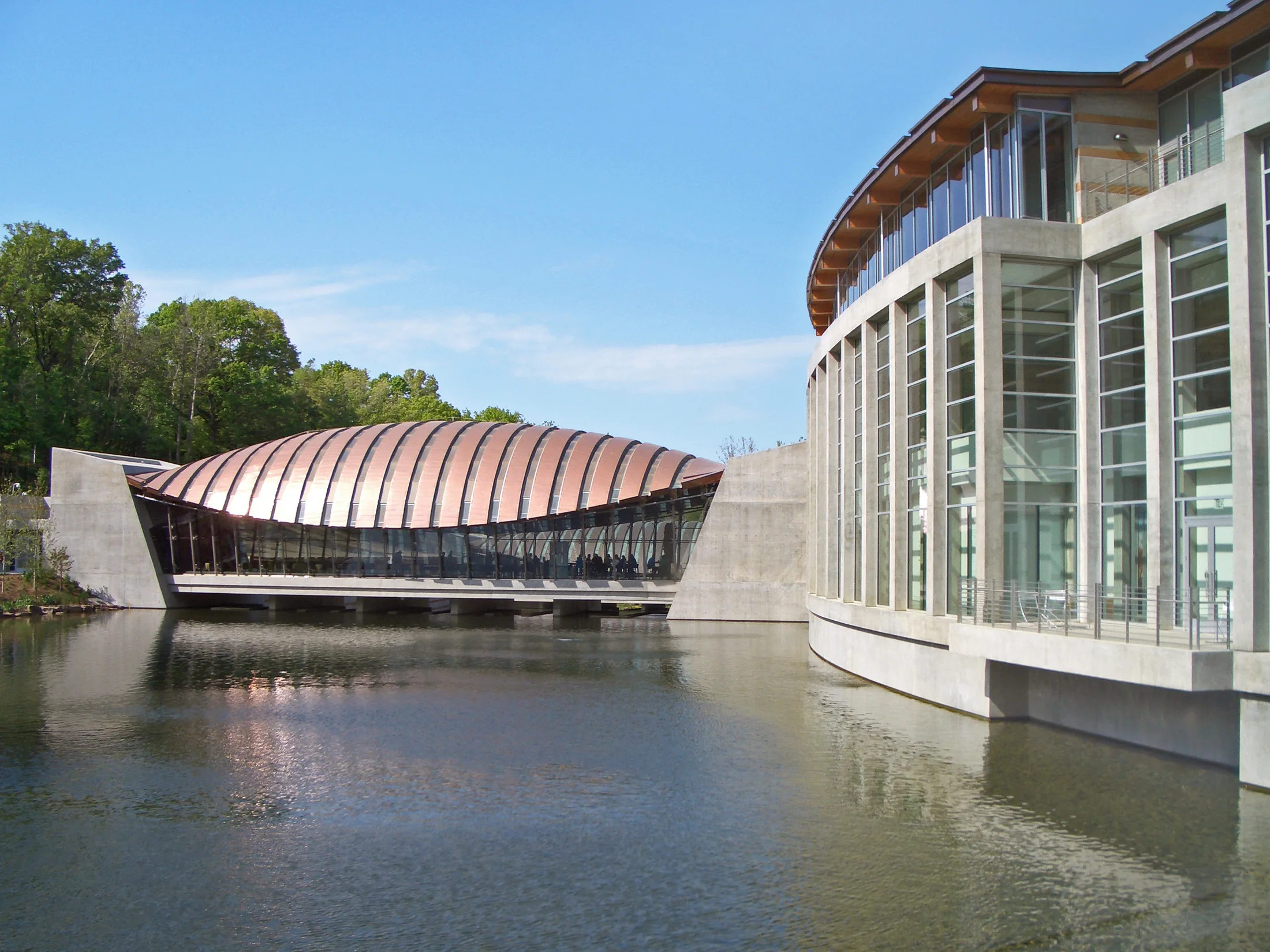 Curved museum pavilions reflected in the water at Crystal Bridges