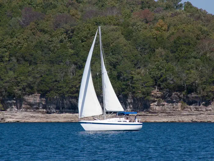 A white sailboat moving across Beaver Lake